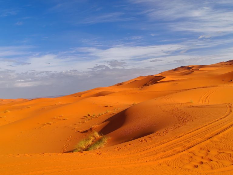 Die Wüste Sahara mit leuchtend orangem Sand und blauem Himmel