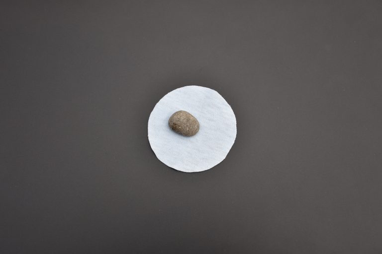 Une petite pierre est posée sur un cercle de tissu découpé.